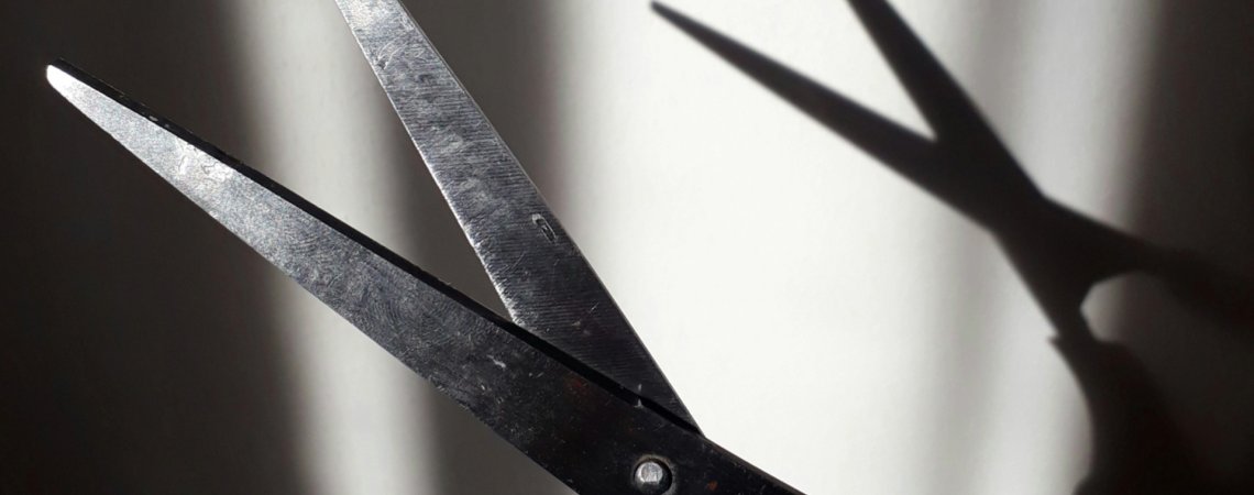 Schere im Vordergrund, die einen Schatten wirft in Schwarz-Weiß